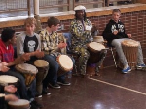 students drumming with a teaching artist in a semi-circle